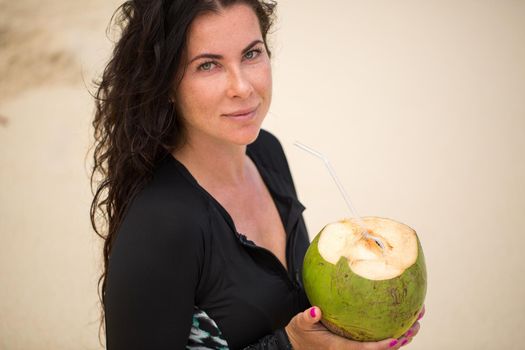 Portrait of a young woman with a coconut in her hands on the beach.