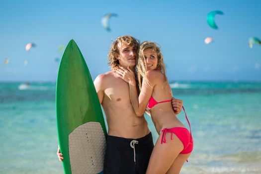 Young couple on beach with surfboard in arm. Surfing and outdoor sport lifestyle concept.