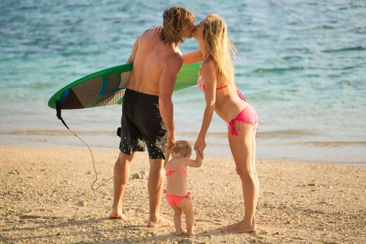 Sports family dad, mom and daughter walking on the beach