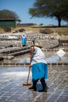 People collect the salt on a Sunny day on the shores of the Indian ocean in Mauritius.