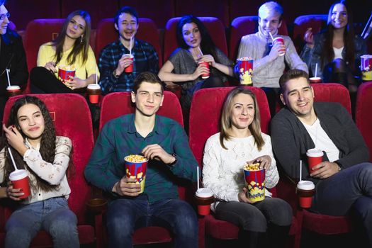 Friends sit in a cinema watch film eating popcorn and drinking aerated sweet water. Movies and entertainment concept