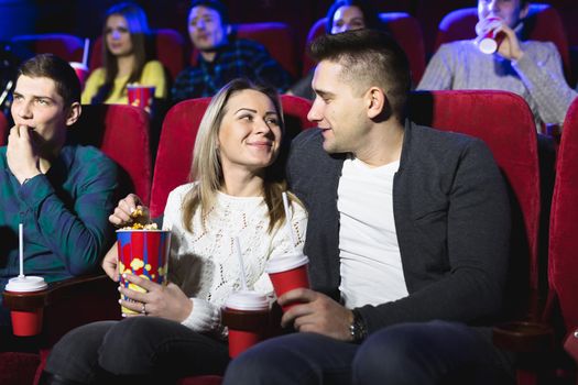 Happy young couple sitting at the cinema and enjoys watching the movie
