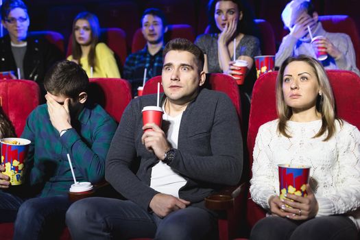 Young scared couple at the cinema watching an horror movie