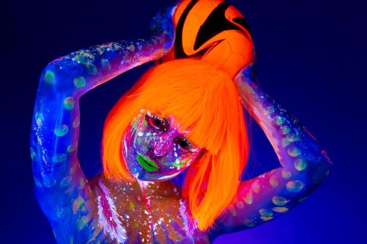 Woman in neon makeup holds a soccer ball in her hands. Concept of the world Cup. Fluorescent paint in UV light