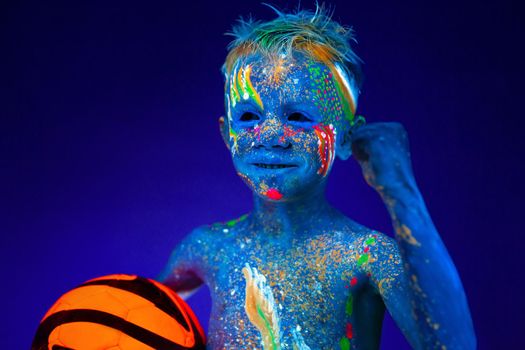 Portrait of a boy in ultraviolet light with a soccer ball. Concept of the world Cup a footbal