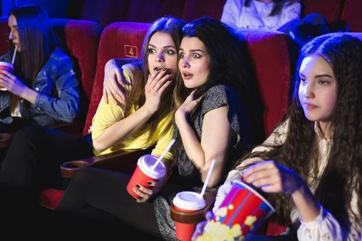 Friends young women in the cinema watching a horror movie