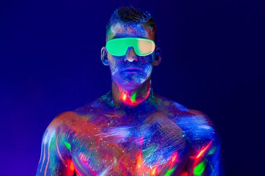 Portrait of a pumped-up man at a disco. Fluorescent paint on face in with UV light