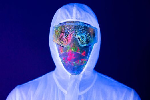 Portrait of man doctor in protective clothes in ultraviolet neon light during coronavirus pandemic. Epidemic, pandemic of coronavirus covid-19