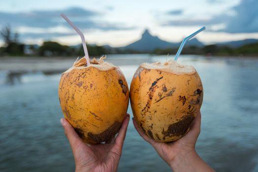 Two fresh coconut cocktail with cocktail straw in his hands