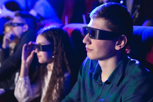 young smiling friends in 3d glasses eating popcorn and watching movie in cinema