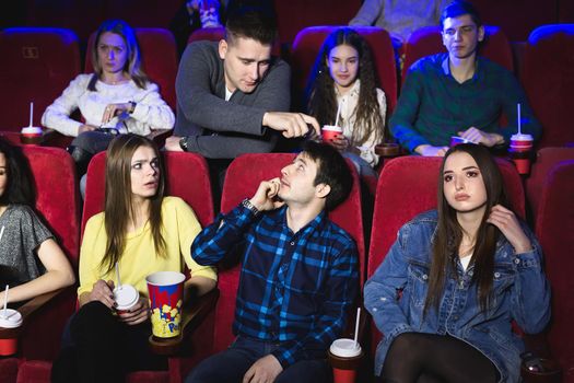 A man is talking loudly on the phone in a movie theater and prevents you from watching a movie. The man makes a remark and asks to turn off the phone.