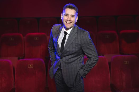 Portrait of a young handsome man alone in a movie theater in a business suit