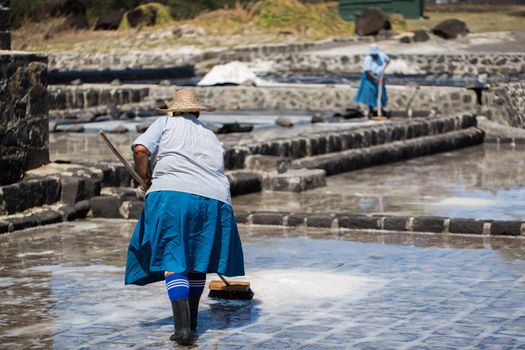 People collect the salt on a Sunny day on the shores of the Indian ocean in Mauritius.