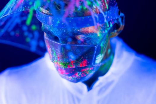 Portrait of man doctor in protective clothes in ultraviolet neon light during coronavirus pandemic. Epidemic, pandemic of coronavirus covid-19