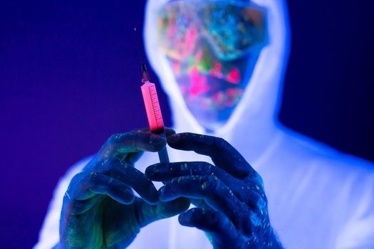 Doctor in ultraviolet neon light is holding COVID-19, oronavirus vaccine and syringe using for prevent infection. Medicine and Healthcare concept