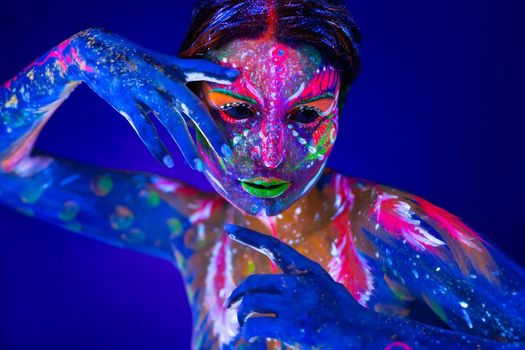 Body art glowing in ultraviolet light. Body art on the body and hand of a girl glowing in the ultraviolet light