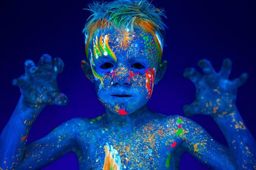 Boy shows the animal tiger, lion. Posing in UV ultraviolet light