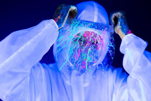 Portrait of woman doctor in protective clothes in ultraviolet neon light during coronavirus pandemic. Epidemic, pandemic of coronavirus covid-19. Doctor, patient in respirator.