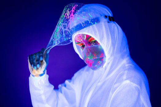 Portrait of woman doctor in protective clothes in ultraviolet neon light during coronavirus pandemic. Epidemic, pandemic of coronavirus covid-19. Doctor, patient in respirator.