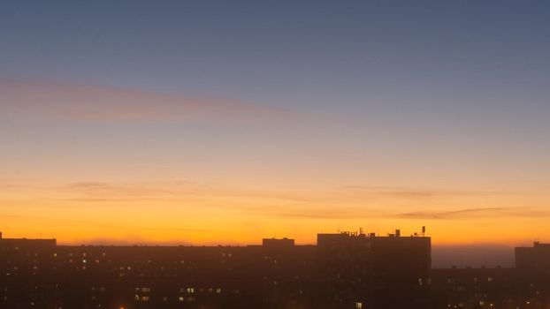 SEVERODVINSK, RUSSIA - MARCH, 11, 2021: Bright winter sunset against the background of houses. Multi-story houses in the rays of the sun. The sun goes down behind the houses