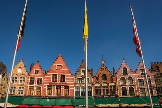 Colourful, traditional Belgian townhouses, buildings and flags in the town square of Bruges, Belgium. High quality photo.