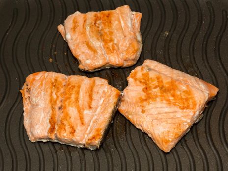 Preparing 3 slices of salmon over iron