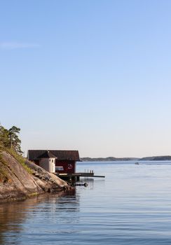 Red Swedish boathouse sitting before the sea in the islands of the Stockholm archipelago, Dalaro, Sweden. High quality photo.