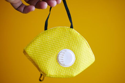 holding yellow color face mask close up .