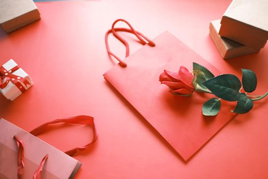 Top view of gift box and rose flower on red background .