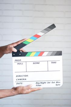 holding Movie clapper board against white wall .