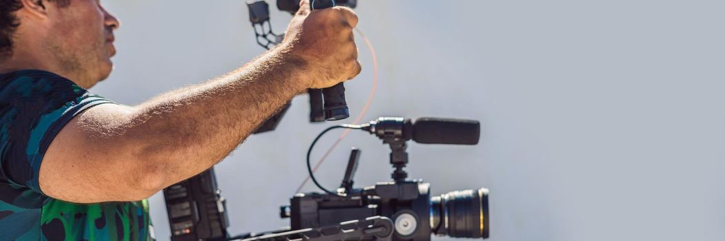 Steadicam operator and his assistant prepare camera and 3-axis stabilizer-gimbal for a commercial shoot. BANNER, LONG FORMAT