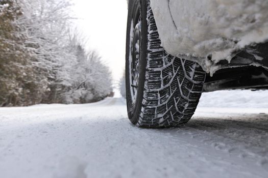Close up of Winter Tire on Snow and Ice Covered Road on a country road. Plenty of copy space. High quality photo