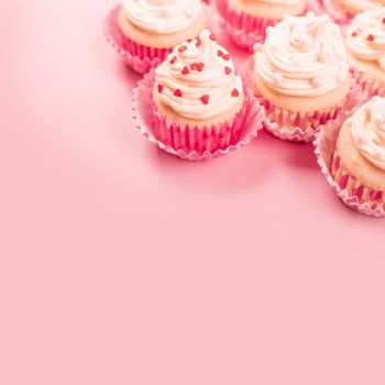 Valentine day love cupcakes decorated with cream and hearts on pink background with copy space for text