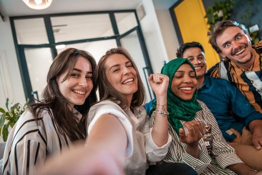 Group of business people during a break from the work taking selfie picture while enjoying free time in relaxation area at modern open plan startup office. Selective focus. High-quality photo