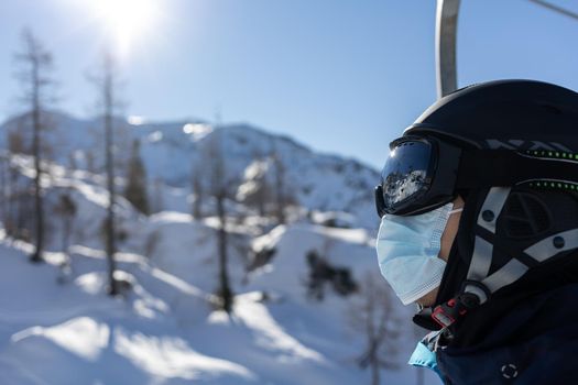 ski resort man portrait on chairlift in helmet and medical mask. High quality photo