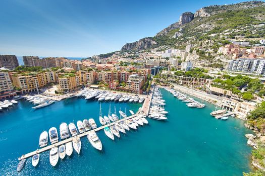 Panoramic image of Port Fontvieille - Monaco, top view from Monaco Ville, azur water, sun reflections on the water, harbour at sunny day, luxury apartments, a lot of yachts and boats, mountain. High quality photo