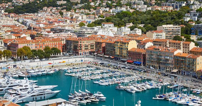 A lot o motor boats and luxury yachts are moored in port of Nice - France at sunny day, mooring ropes go into the amazing azure water, prows of motor boats in a row, roofs of orange color. High quality photo