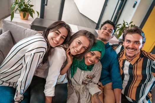 Group of business people during a break from the work taking selfie picture while enjoying free time in relaxation area at modern open plan startup office. Selective focus. High-quality photo