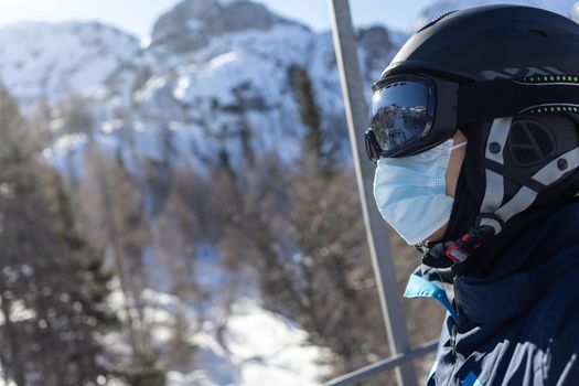 ski resort man portrait on chairlift in helmet and medical mask. High quality photo