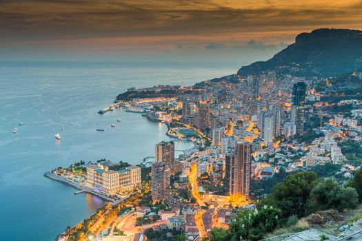 Aerial view of Monaco - Monte-Carlo at dusk, cityscape with night illumination, mountain, skyscrapers, mediterranean sea. High quality photo