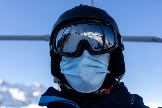 ski resort man portrait on chairlift in helmet and medical mask. High quality photo