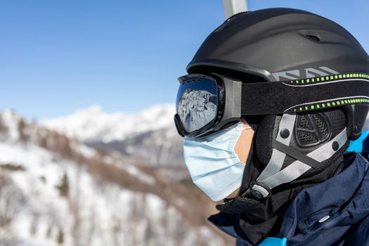 ski resort man portrait on chairlift in helmet and medical mask. High quality photo