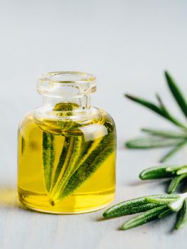 Rosemary oil. Rosemary essential oil oil in small glass bottle and branches of plant fresh rosemary on white background. Copy space for text. Vertical.
