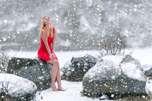 young beautiful woman in red dress by the snowy frozen lake in winter.