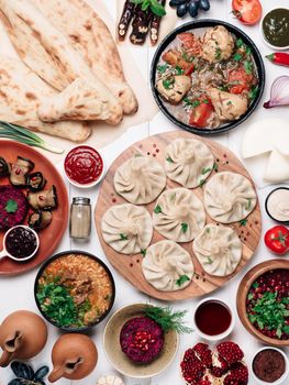 View from above of georgian cuisine on white wooden table. Traditional georgian cuisine and food-khinkali,kharcho,chahokhbili,phali,lobio and local sauces-tkemali,satsebeli,adzhika. Top view. Vertical