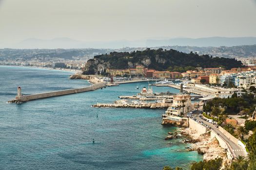 The ferry terminal in port Nice - France at sunny day, A lot o motor boats and luxury yachts are moored in port, mooring ropes go into the amazing azure water, famous embankment and lighthouse. High quality photo