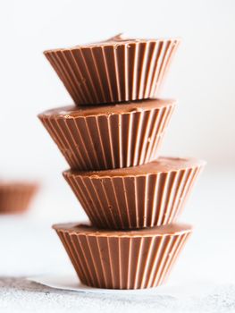 Stack of vegan chocolate cups with caramel on white tabletop. Homemade vegetarian chocolate caramel cups. Ideas and recipes for healthy sweets and dessert. Selective focus, Shallow DOF.