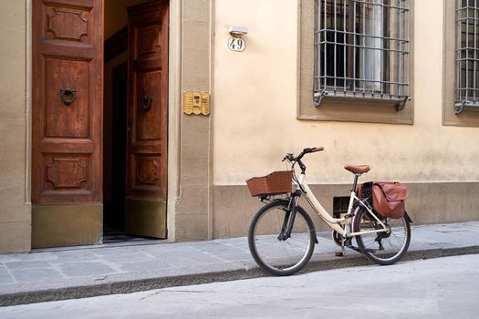 Bicycle with basket and leather bag or pannier parked on the old street in Italy