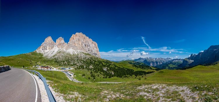 Ultra wide panorama of picturesque road through the Sella Pass in Dolomites with text space, Italy