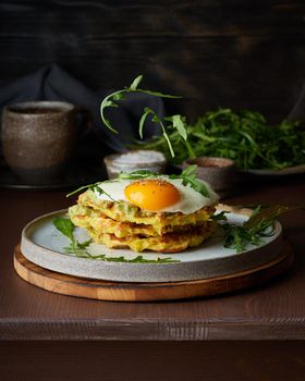 Homemade potato belgian waffles with fried egg, avocado sauce, flying arugula, mozzarella cheese. Levitation. Hearty fat breakfast. Dark brown table. Close up, vertical, copy space